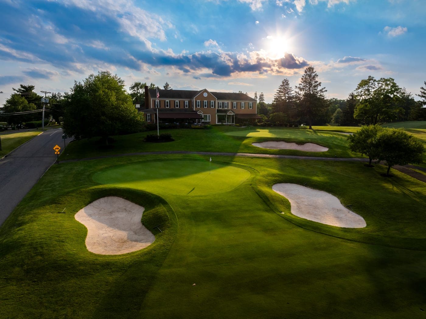 An aerial view of the Copper Hill clubhouse at sunset, with the practice green and bunkers in the foreground.