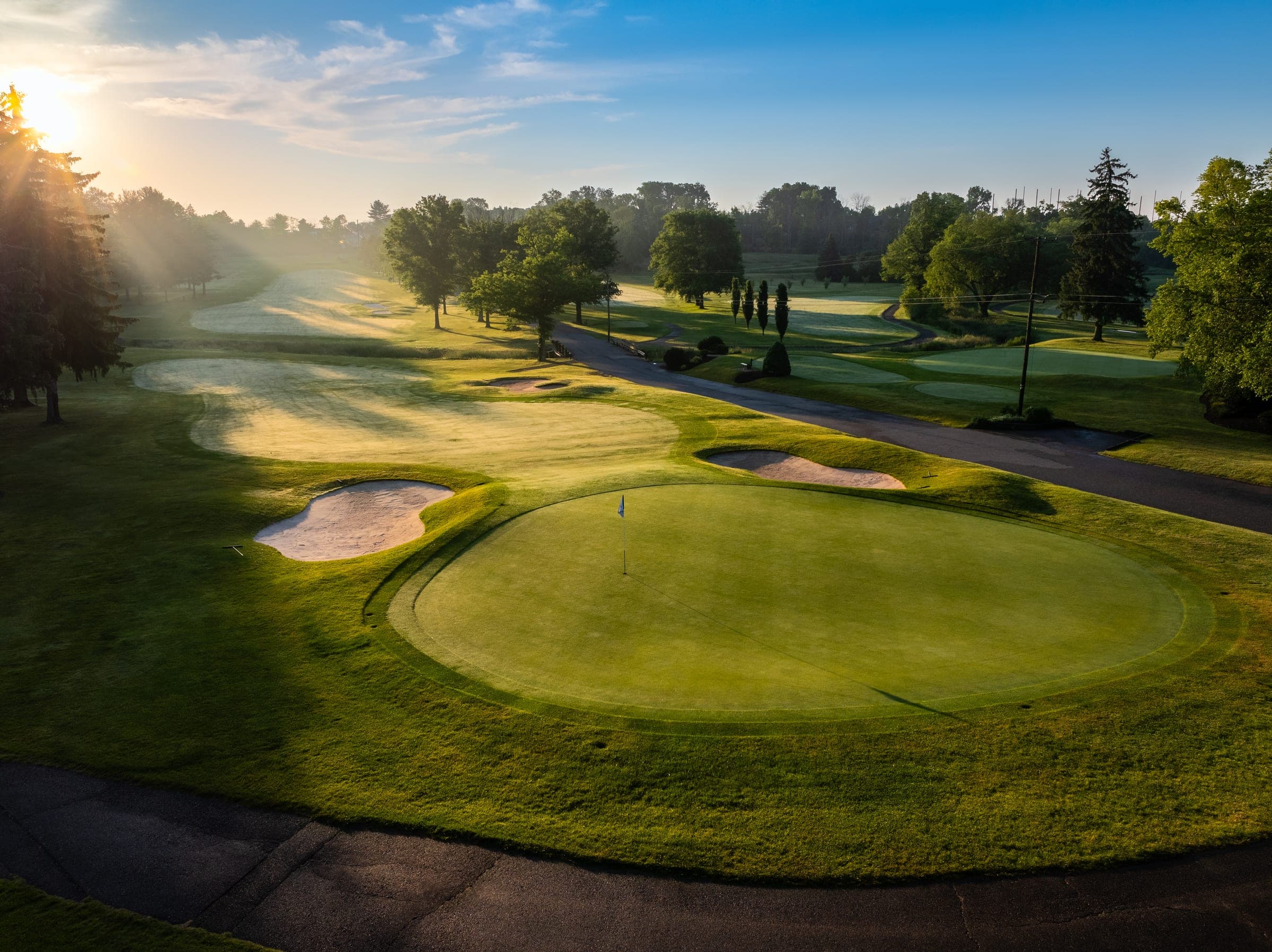 A Copper Hill fairway at sunrise, mist over the grass and the pin flag catching the first light.